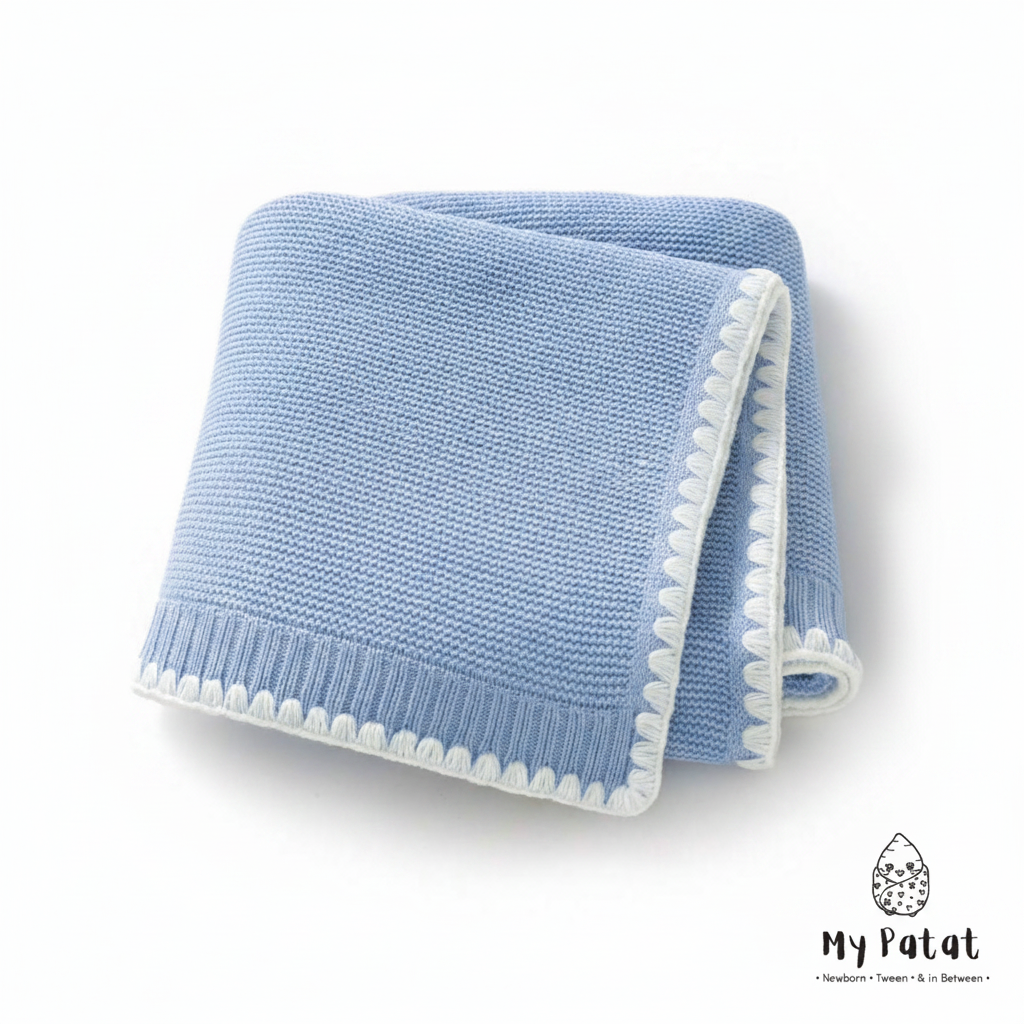 Blue knit baby blanket with white pom-pom trim