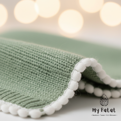 Knit baby blanket pom-pom trim close-up