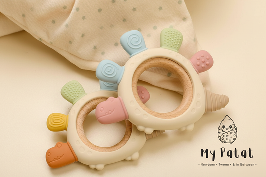 Two silicone baby teething rings on a soft cream polka dot blanket with My Patat Shop logo