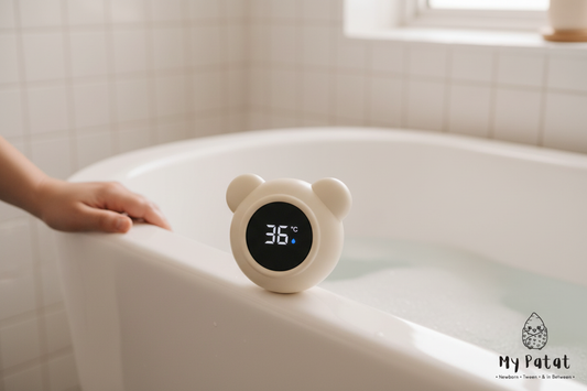 Bear baby thermometer sitting on edge of white bathtub with warm water