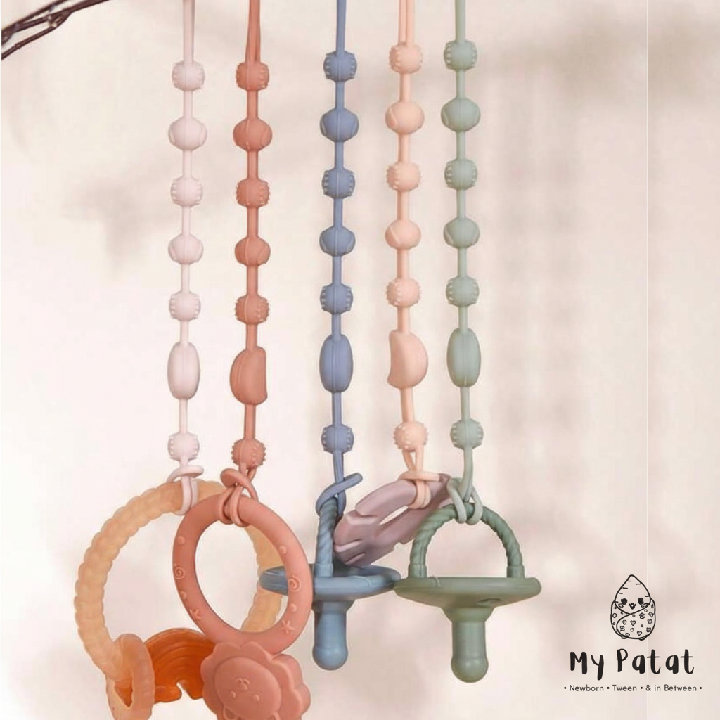 Silicone soother chains hanging with teething rings and dummies in pastel colours