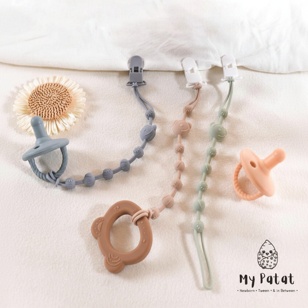 Silicone dummy clip chains on white linen with dried sunflower and teether