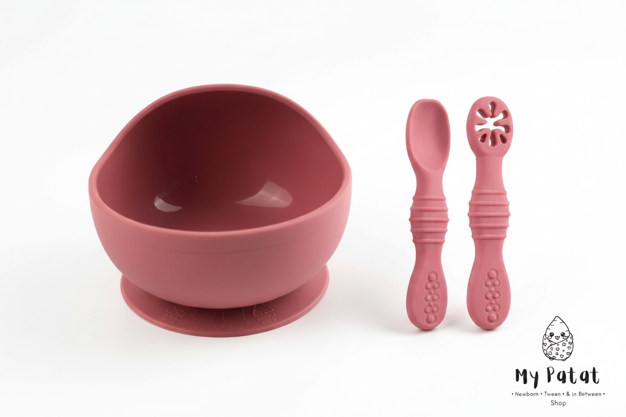 Rose pink silicone baby suction bowl and spoons on white background
