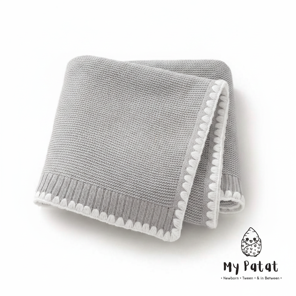 Grey knit baby blanket with white pom-pom trim